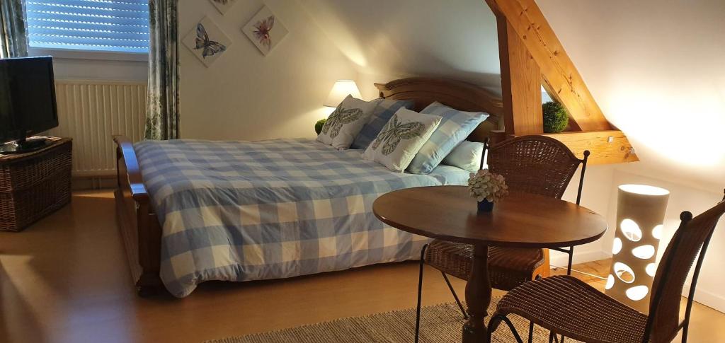 a bedroom with a bed and a table and a television at Maison des Hortensias in Saint-Contest