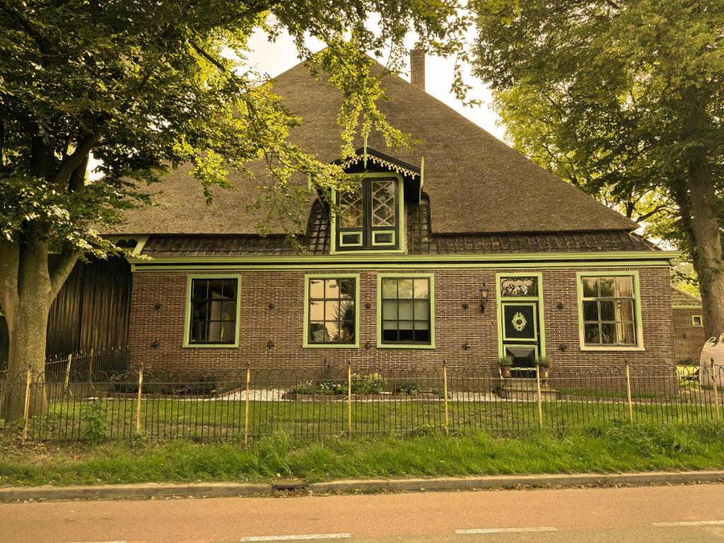 a brick house with a black roof at De Noorderzon in Benningbroek