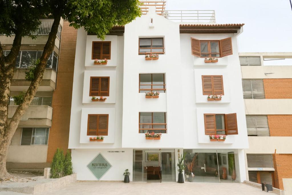 a white building with windows and a tree at Riviera Hotel Boutique in Cali