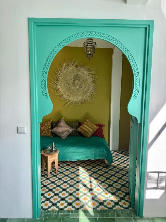 a bedroom with a green bed and a yellow wall at Dar Raphael in Essaouira