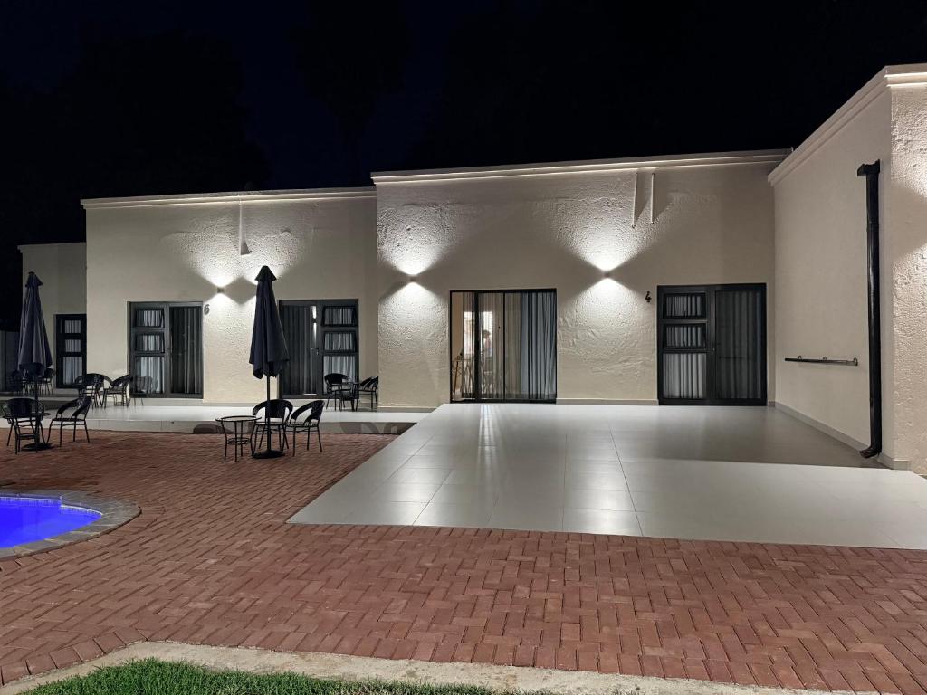 a large white building with chairs and tables at night at Cathy & P Guesthouse in Hartbeespoort