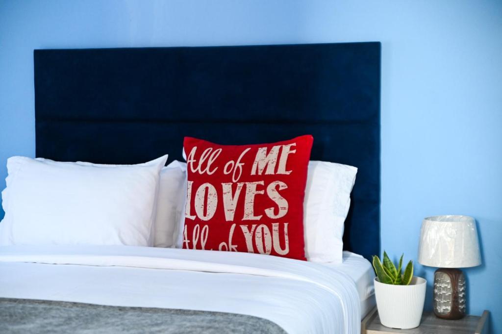 a bed with a red pillow that reads till of he loves you you at Luxe Residence Guest House in Kasane