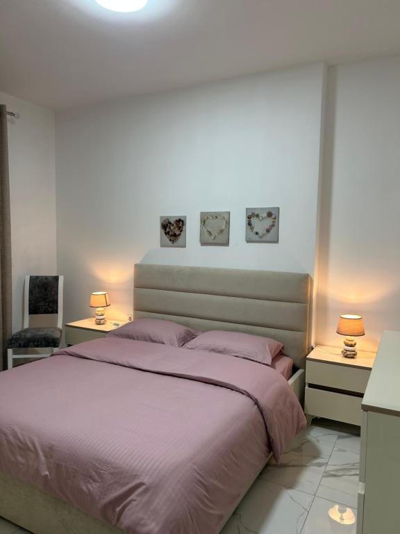 a bedroom with a bed with purple sheets and two lamps at Apartment Elis in Kamëz
