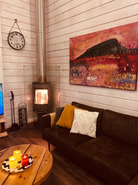 a living room with a couch and a table and a clock at Unelmasäleikkö 2 in Kittilä