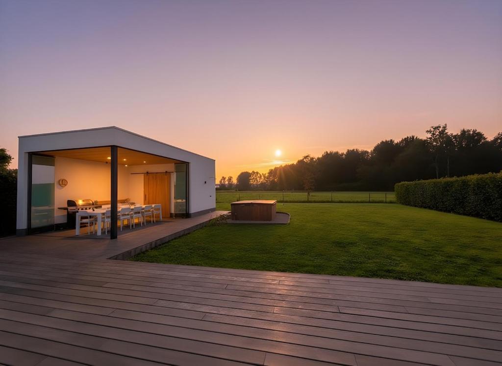 a modern house with a sunset in the background at Luxe Villa Tramonto with jacuzzi in Sint-Truiden