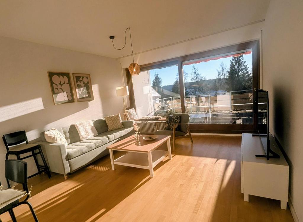 a living room with a couch and a table at Wohnen am Wald mit Pool & Sauna in Unterkirnach