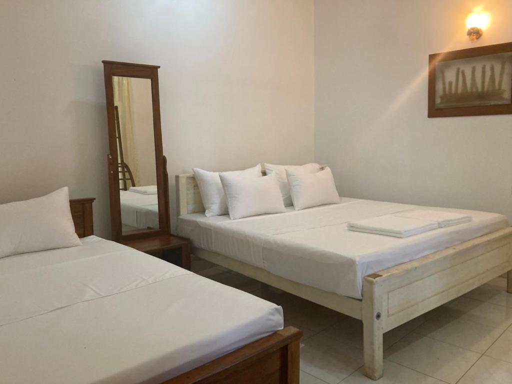 a bedroom with two beds and a mirror at TENBY Guest House in Anuradhapura