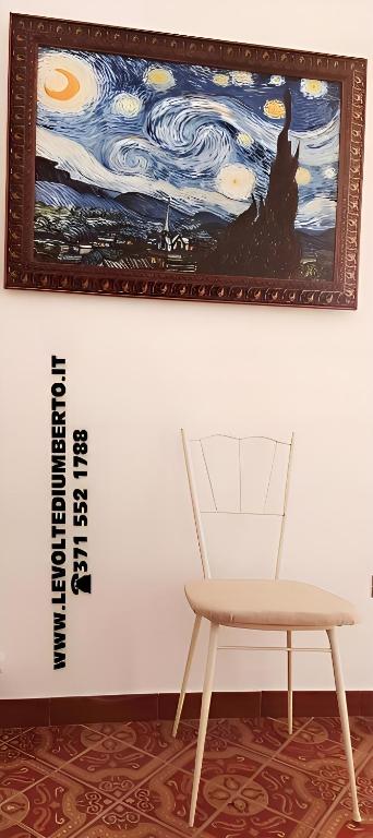 a chair and a painting on a wall next to a table at Le volte di Umberto Tramontana in Sogliano Cavour