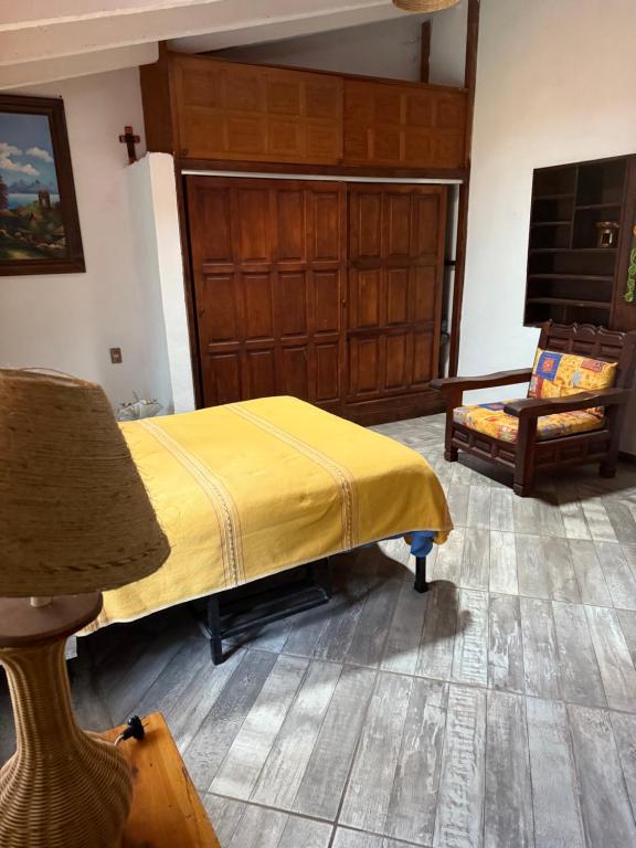 a bedroom with a bed with a yellow blanket on it at House 3 blocks from downtown in Tepoztlán