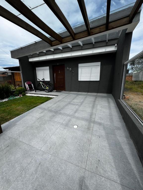 a house with a large concrete driveway at Excelente casa com piscina próx ao Mar in Capão da Canoa