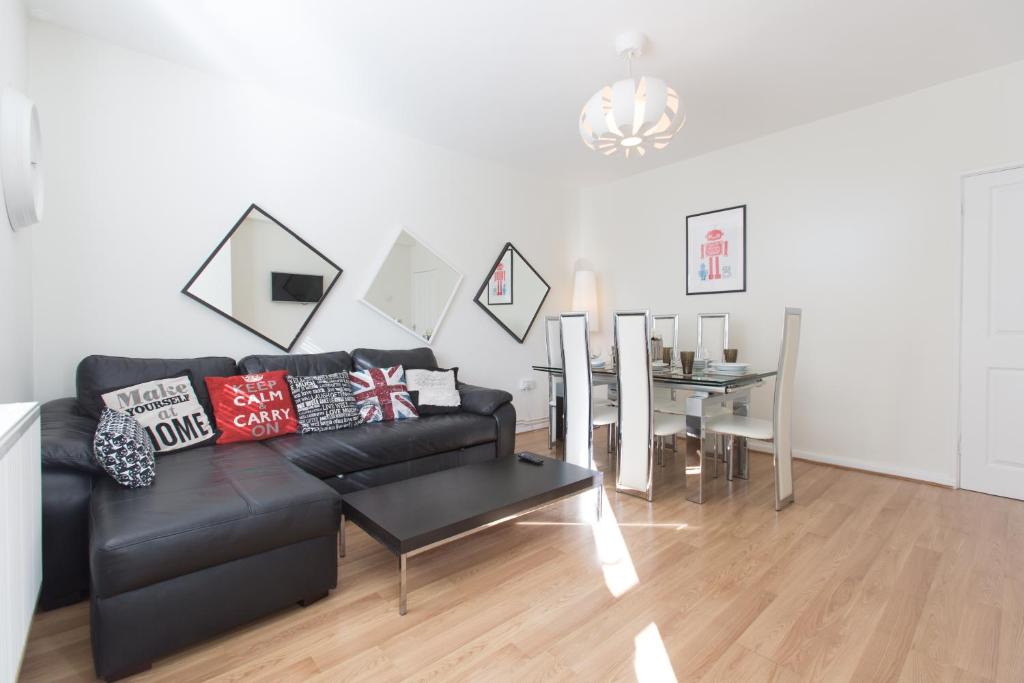 ein Wohnzimmer mit einem schwarzen Sofa und einem Tisch in der Unterkunft BEST LOCATION Central London Zone 1 Large 3 bedroom near all Attractions in London