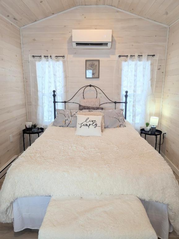 a bedroom with a large bed with two windows at Field and Fern Cottages in Tatamagouche