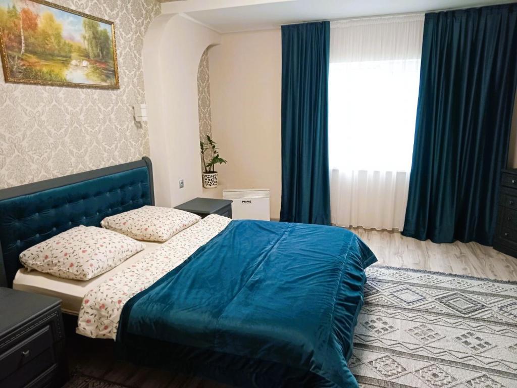 a bedroom with a blue bed and a window at Котедж Тиша in Rivnya