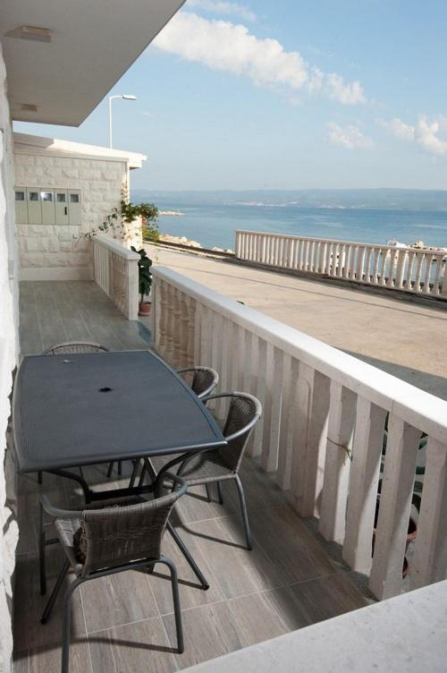a table and chairs on a balcony with the ocean at Apartmani Ivo 2 in Podstrana