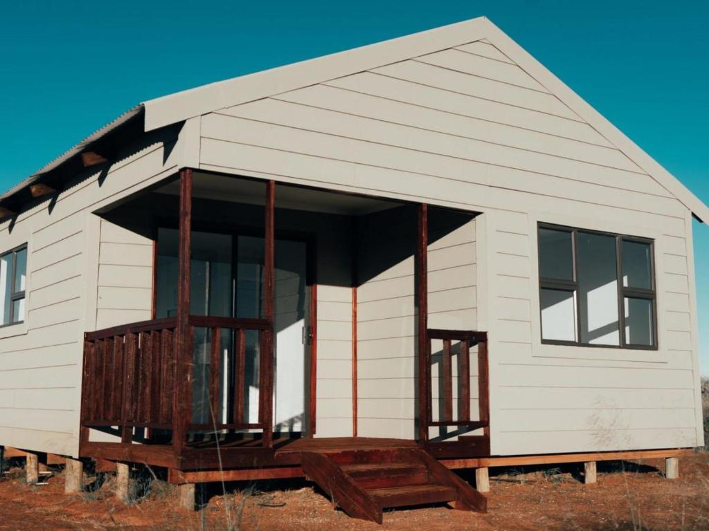 a small white house with a porch and a bench at Kwagae farm in Kuruman