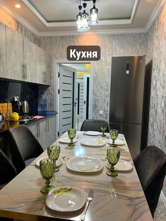 a kitchen with a table with plates and a refrigerator at Gagarin Luxury Apartment in Samarkand
