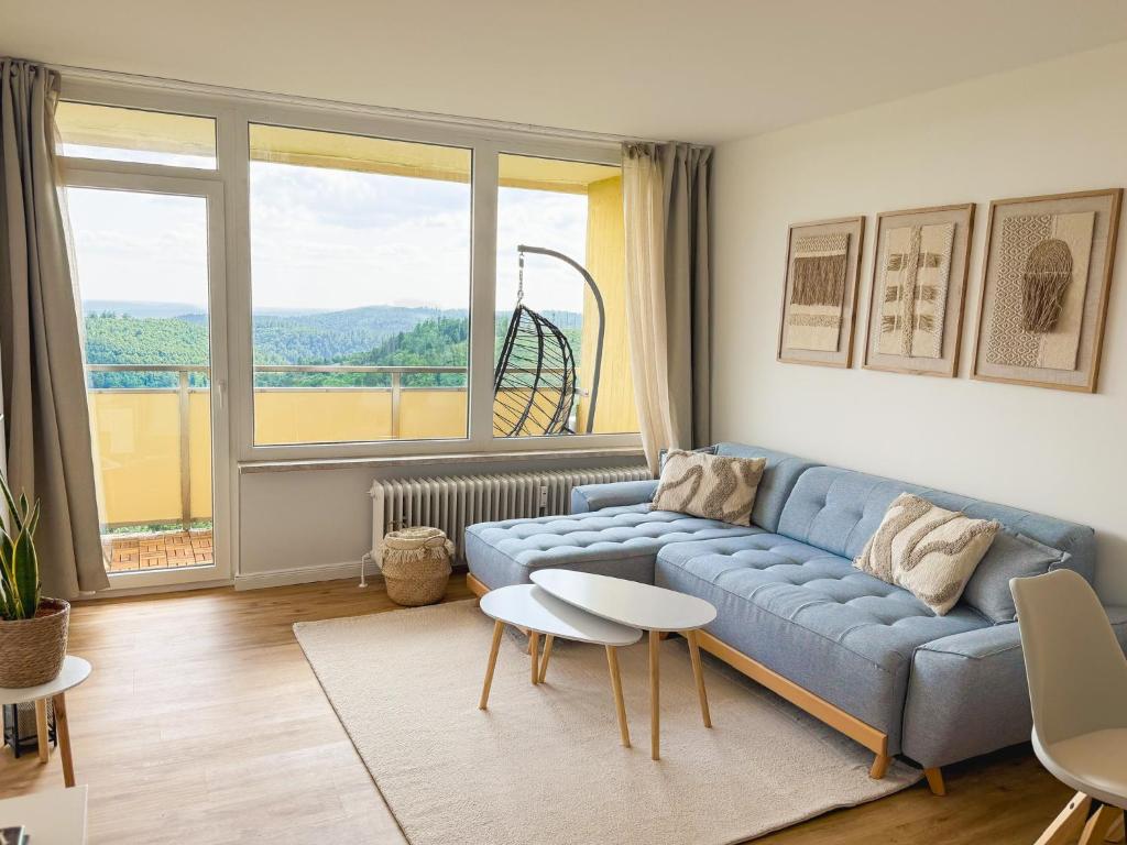 a living room with a blue couch and a large window at Apartment Rehberg 14 OG Panorama Balkon Pool Sauna in Braunlage