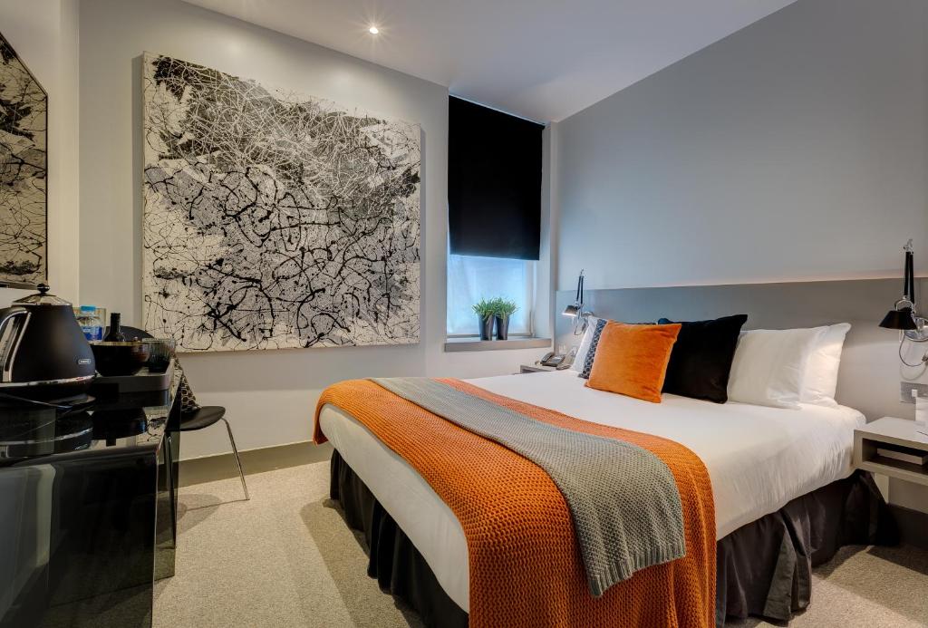 a bedroom with a large bed with an orange blanket at Hotel 55 in London