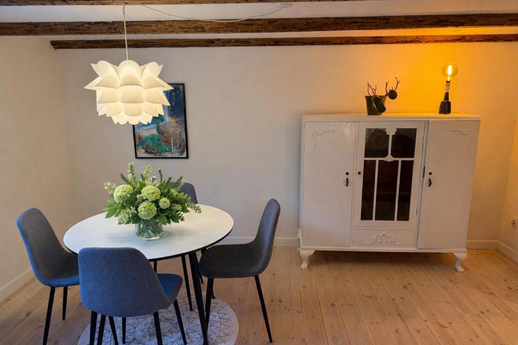 a dining room with a table and chairs and a chandelier at Villa Fuga kælderlejlighed in Jelling