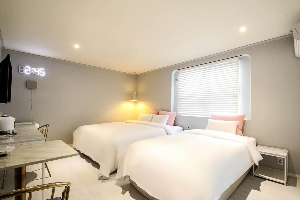 two beds in a small room with a table and a tableablish at MoMo Juice Busan Haeundae in Busan