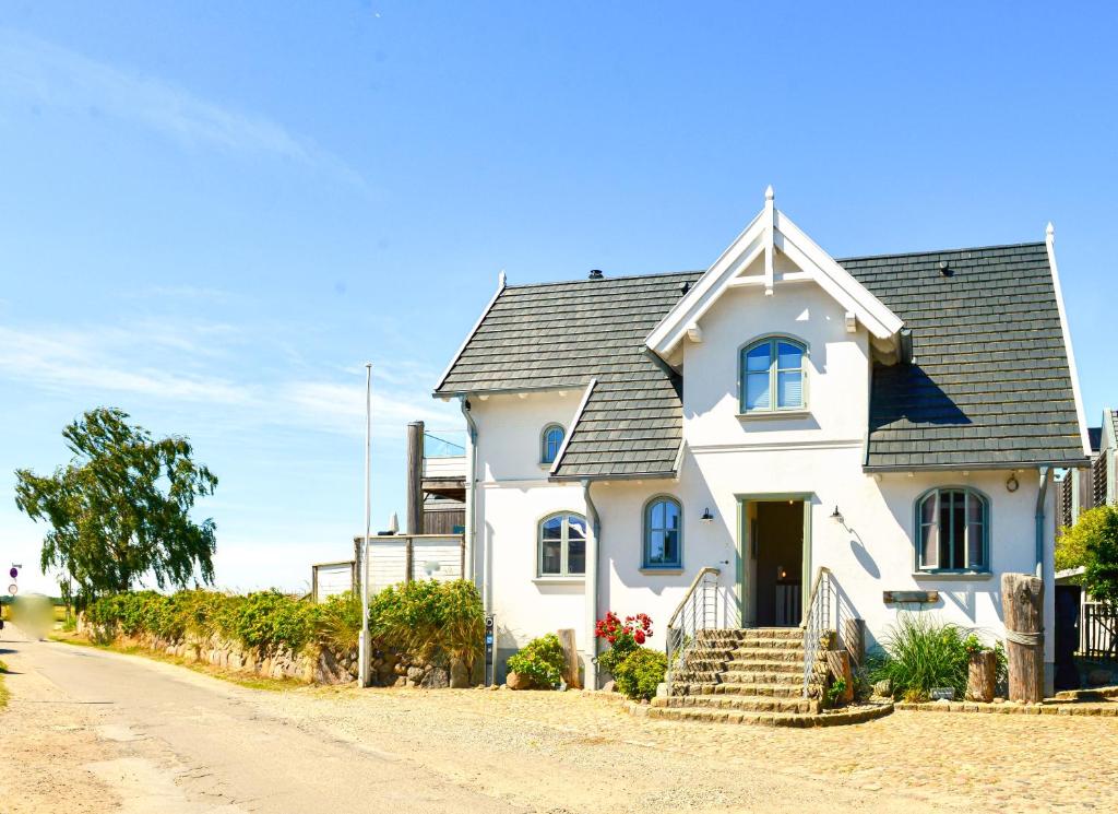 a white house with a gray roof on a dirt road at BEACHHOUSE Fehmarn in Fehmarn