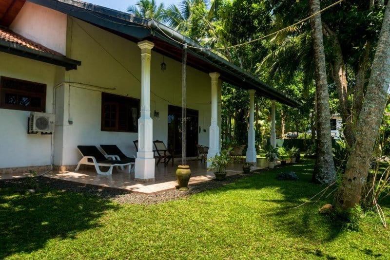 a house with a porch with a swing at Hikka Magnoon Villa in Hikkaduwa
