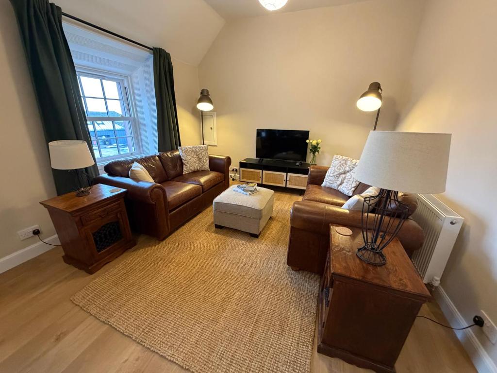 a living room with couches and a television at Roods Apartment in Angus