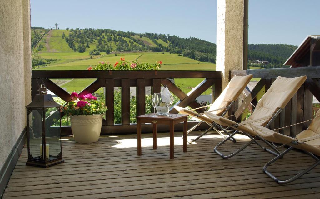 a deck with two chairs and a table and flowers at Hotel Magdalenenhof inklusive MeineCardPlus in Willingen