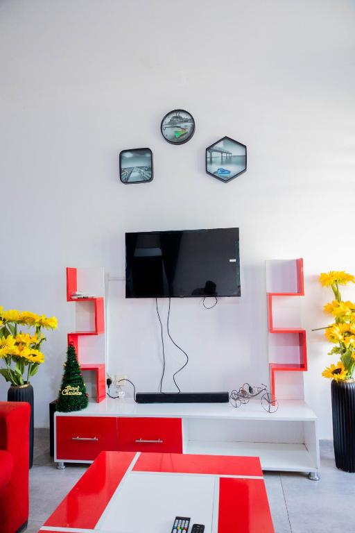 a living room with red furniture and a tv on a wall at Eli Villa in Abia