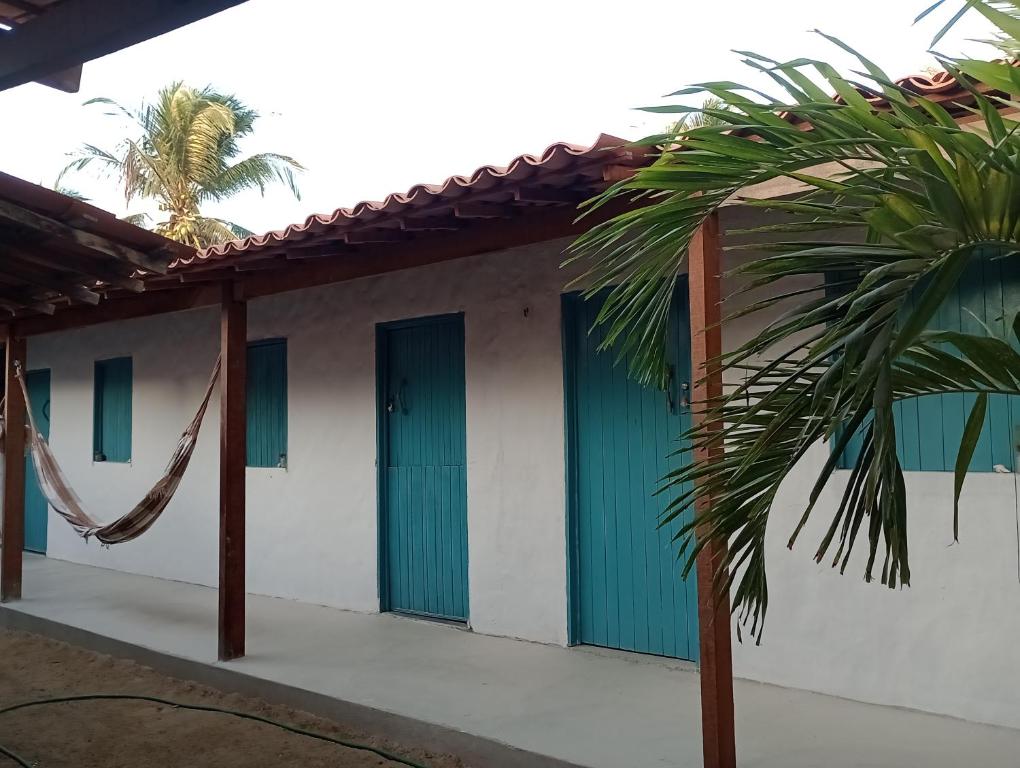 a house with green doors and a hammock at Pousada Infinito Azul in Prea