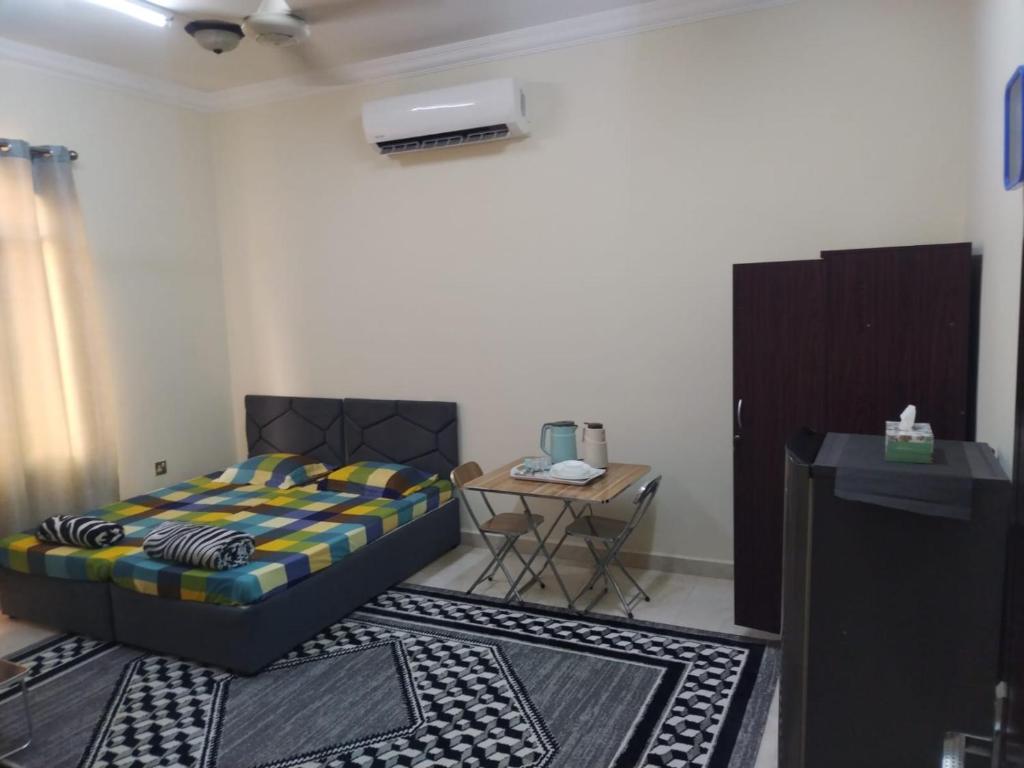 a bedroom with a bed and a table with a desk at Private Rooms For Rent Near Airport - Raha Hostel in Ḩayl Āl ‘Umayr