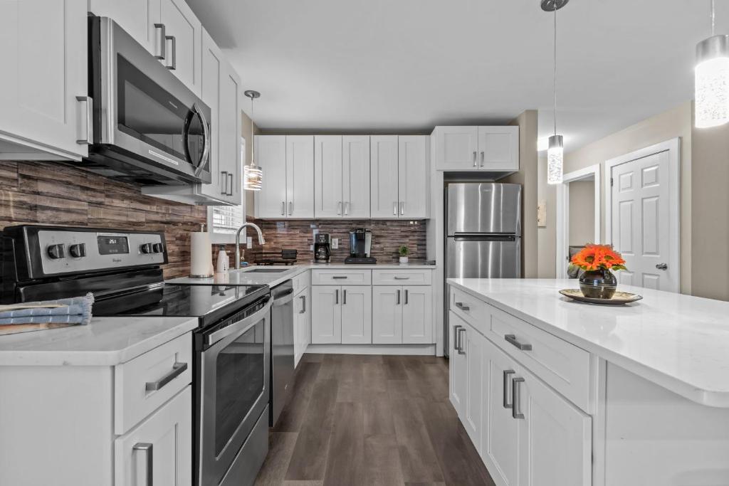 a kitchen with white cabinets and white counter tops at Evergreen Villa Poconos - Hot Tub, Fire Pit, Close to Kalahari, Great Wolf Lodge and Camelback in Tobyhanna
