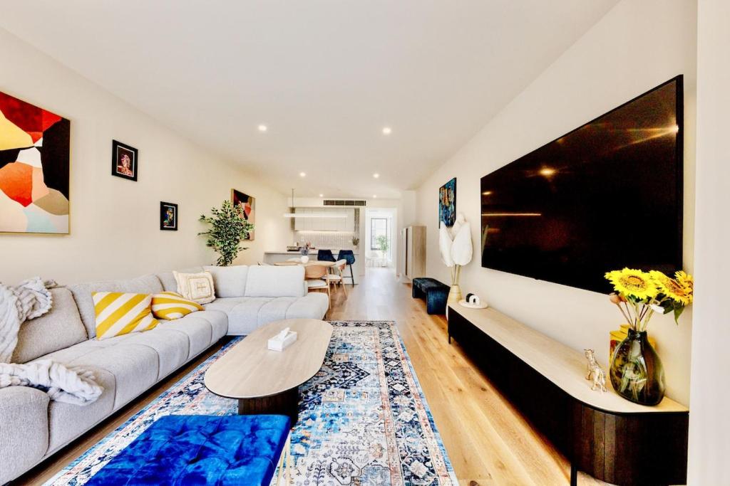 a living room with a couch and a tv at Splendid Spacious - Port Melbourne Beachside Home in Melbourne