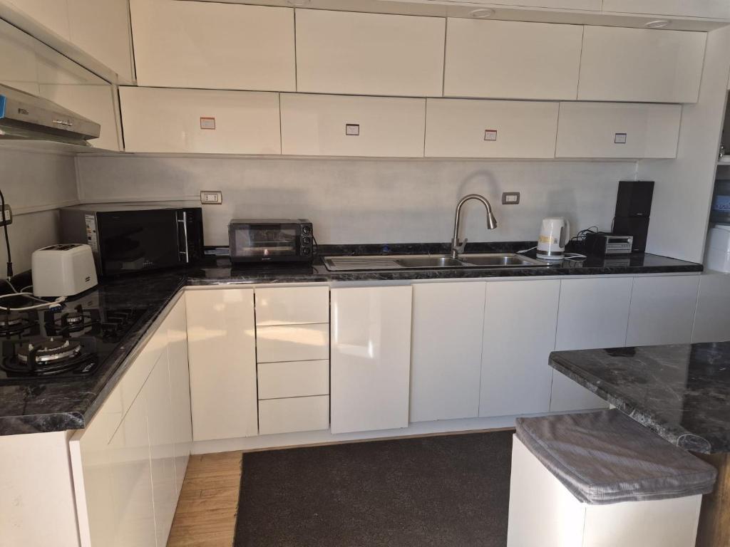 a kitchen with white cabinets and a sink at Alojamiento Costanera in Laraquete