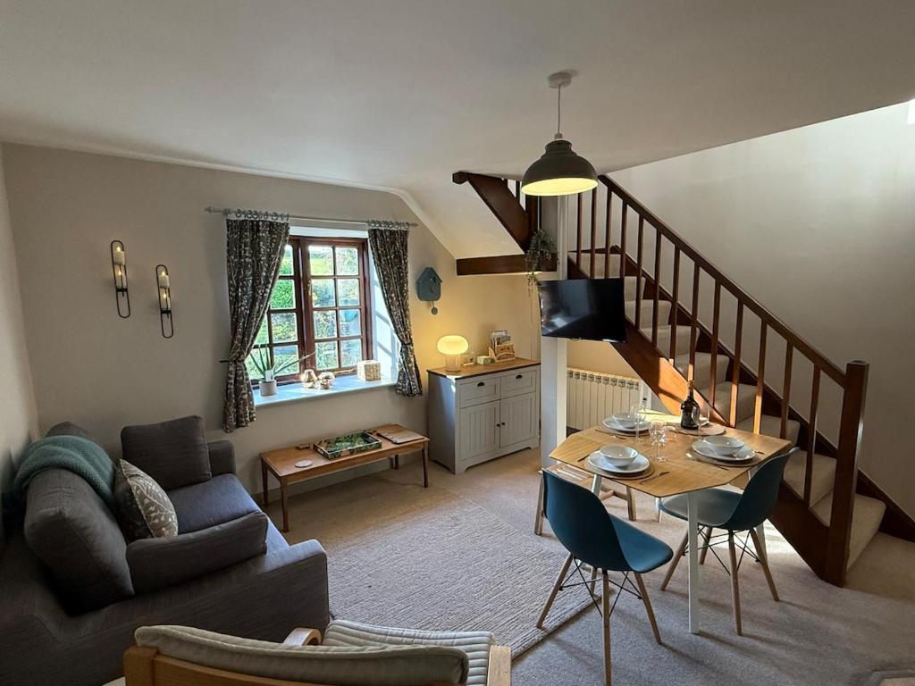 a living room with a couch and a table and a staircase at 2 Nookdales Cottages in Ingleton