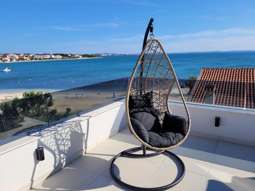 a hanging chair on a balcony overlooking the ocean at VIRCATION Apartments in Vir