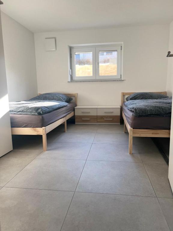 a room with two beds and a window at Gästehaus Wain I Monteur- & Ferienwohnung für 5 I 2 SZ I Terrasse I Parkplatz I WLAN in Wain