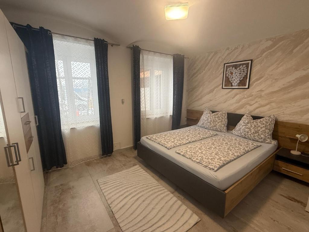a small bedroom with a bed and two windows at Wohung Leonard in Schwanenstadt