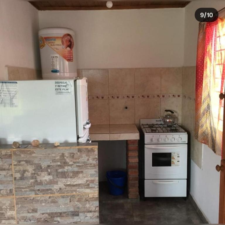 a small kitchen with a refrigerator and a stove at Cabañas Cosquín in Cosquín