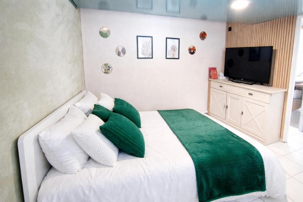 a bedroom with a bed with green and white pillows at Studio en campagne in Retournac