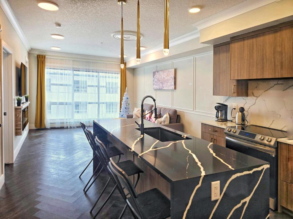 a kitchen with a sink and a counter with chairs at Family Stylish 1BR and Den Condo -Apartment with City View, Downtown, Balcony, Free Parking, In-Suite Laundry! in Calgary