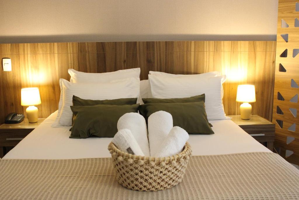 a bedroom with a bed with two towels in a basket at ApartHotel - Nobile Suites Monumental Brasília in Brasília