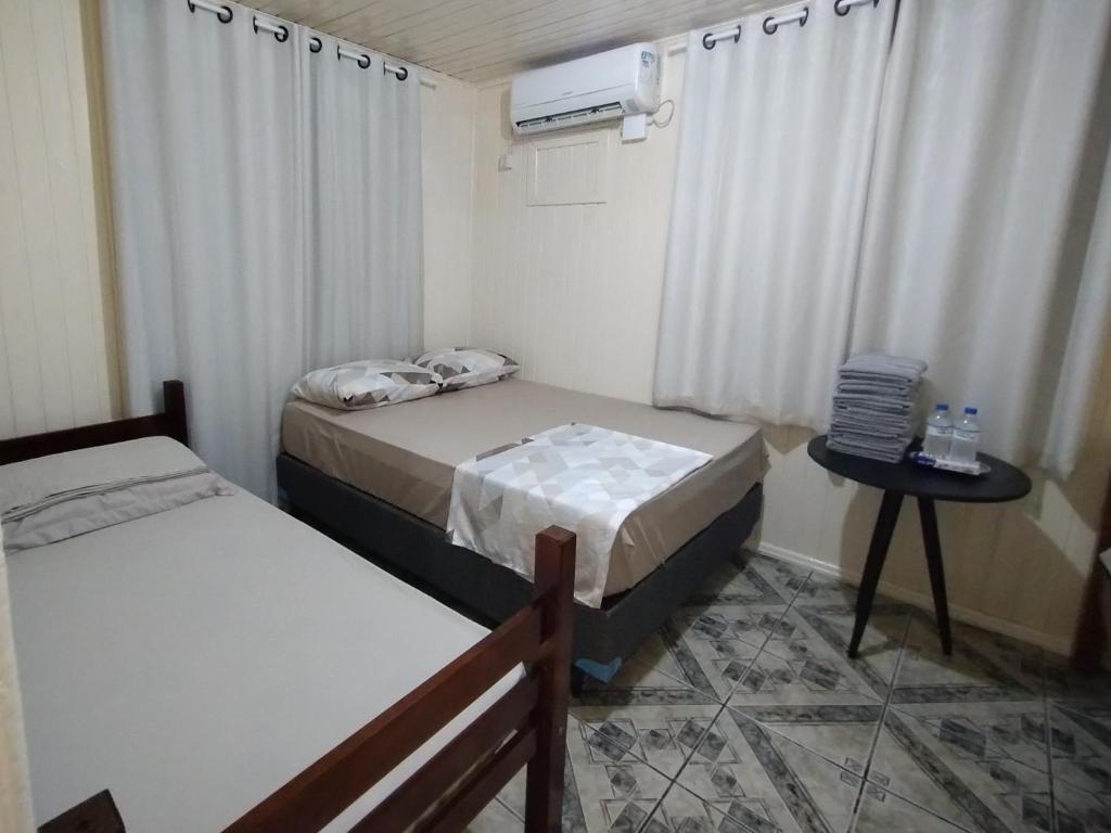 a room with two beds and a table with a window at Chalé com garagem fechada in Pântano Grande