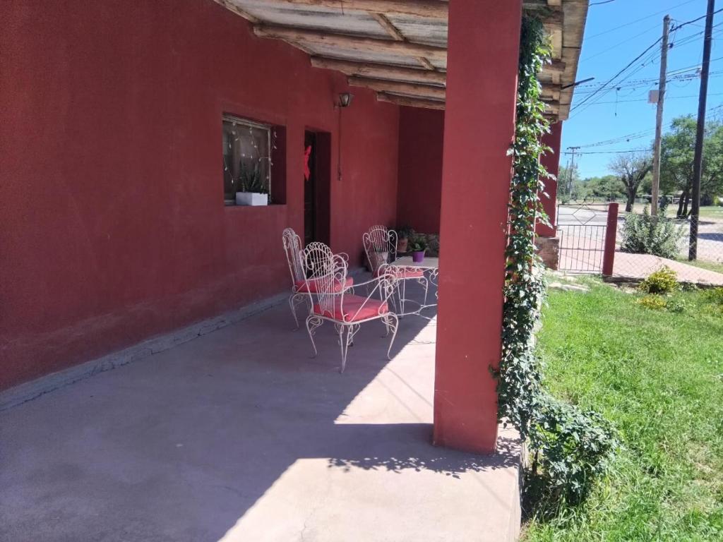 a red building with tables and chairs on a patio at Casona Estación Cabra Corral in Coronel Moldes