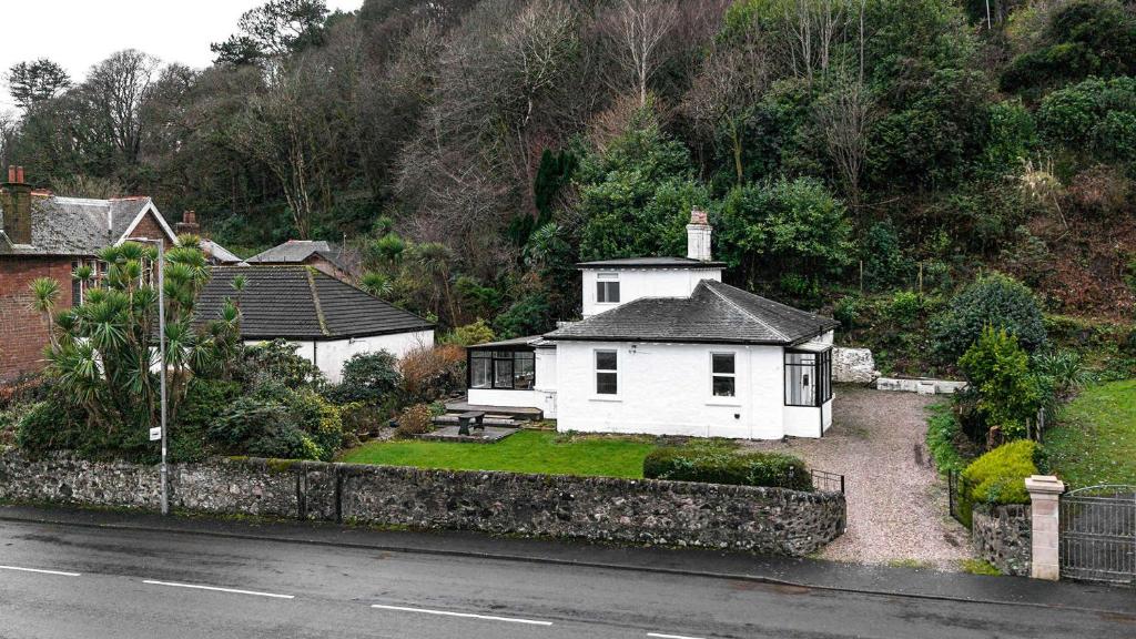 a white house sitting on the side of a road at Craigend Cottage in Rothesay