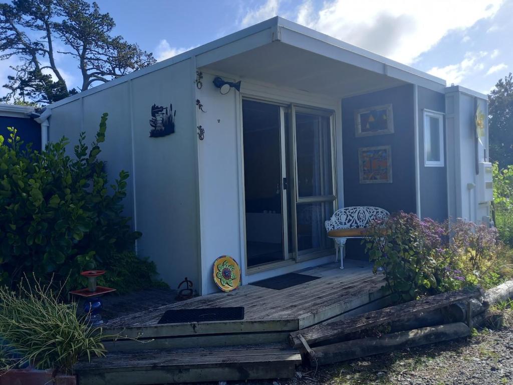 a small blue shed with a bench on a deck at Round About in Parore