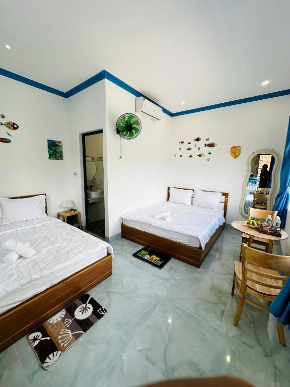 a bedroom with two beds and a table and chairs at Homestay xóm nhỏ in Ninh Hải