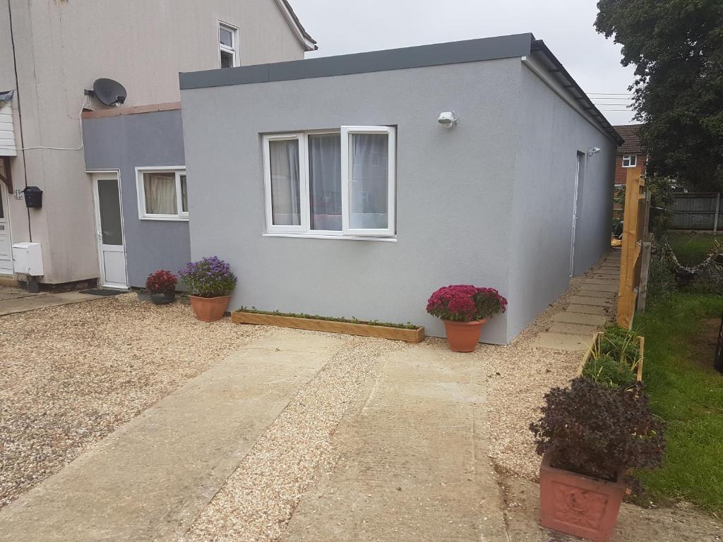 a house with two potted plants in front of it at The Lily Pad apartment & Wrens Nest studio in Swindon