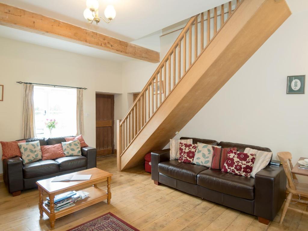 a living room with two couches and a staircase at The Stable in Foxham