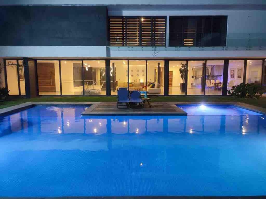 a large pool with two chairs in front of a building at Casa para 16 personas con alberca climatizada in Guadalajara
